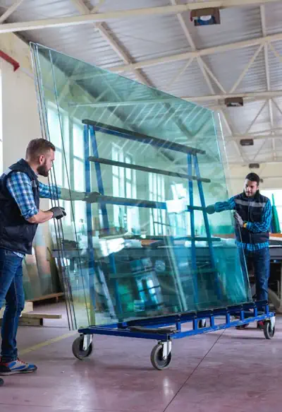 Commercial glaziers carrying a large panel of double glazed glass in to a warehouse in Bunbury